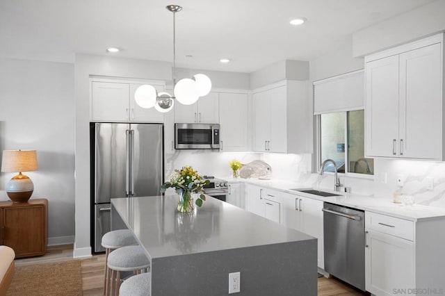 kitchen featuring pendant lighting, appliances with stainless steel finishes, a center island, and sink