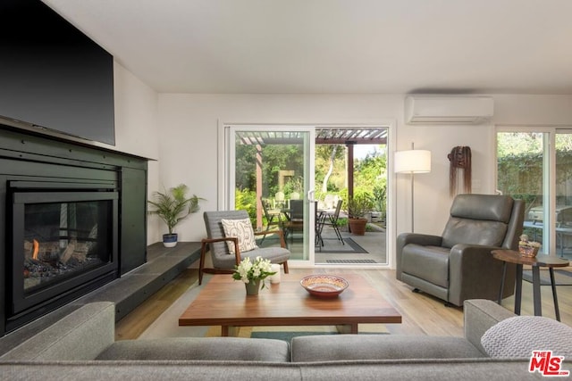 living room with a wall unit AC and light hardwood / wood-style floors