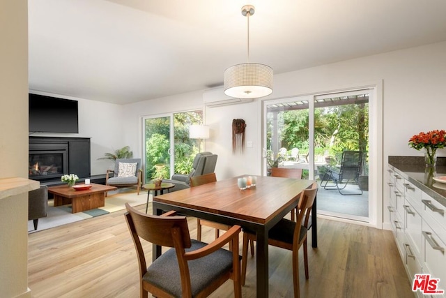 dining space with plenty of natural light, an AC wall unit, and light hardwood / wood-style floors