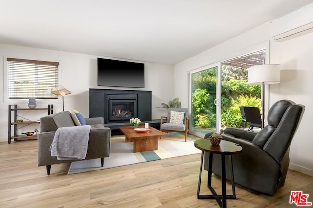 living room with a wealth of natural light, a wall unit AC, and light hardwood / wood-style floors