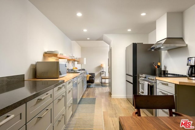 kitchen featuring stainless steel appliances, gray cabinetry, light hardwood / wood-style floors, and wall chimney exhaust hood