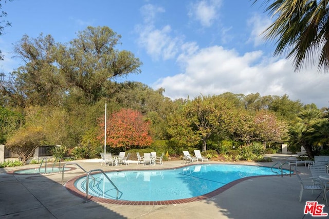 view of swimming pool featuring a hot tub and a patio area