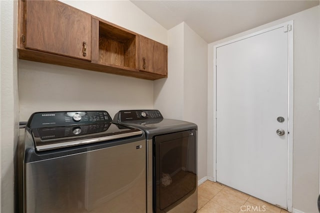 laundry room featuring cabinets, light tile patterned flooring, and separate washer and dryer