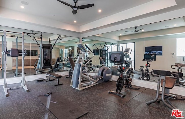 gym with ceiling fan and a tray ceiling