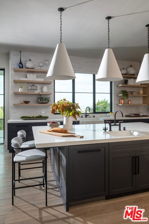 kitchen with sink, backsplash, light hardwood / wood-style floors, and decorative light fixtures