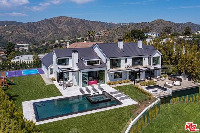 back of house with a mountain view, a yard, a patio area, and a pool with hot tub