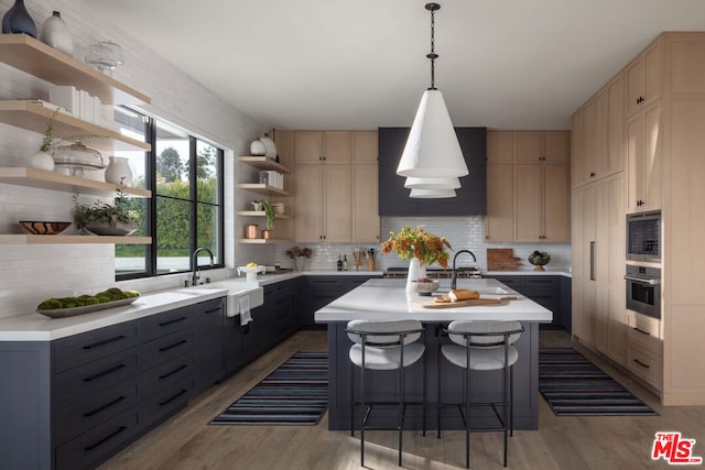 kitchen with a breakfast bar, gray cabinets, an island with sink, pendant lighting, and oven