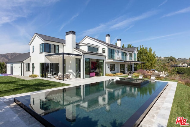 rear view of property featuring a lawn and a patio area