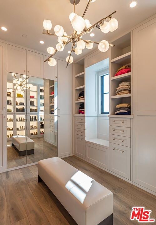 spacious closet featuring an inviting chandelier and hardwood / wood-style flooring