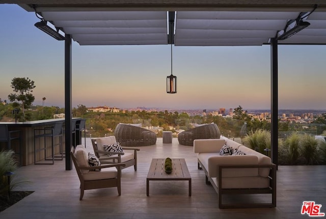 patio terrace at dusk featuring an outdoor living space, exterior bar, and a pergola