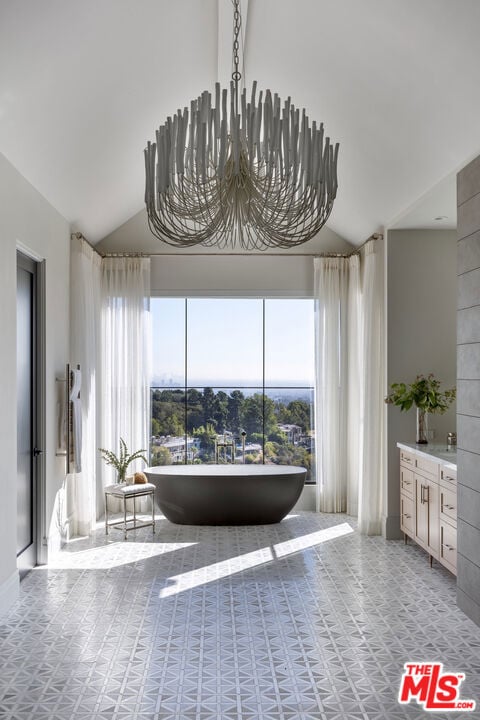 bathroom with vanity, a washtub, vaulted ceiling, and a chandelier