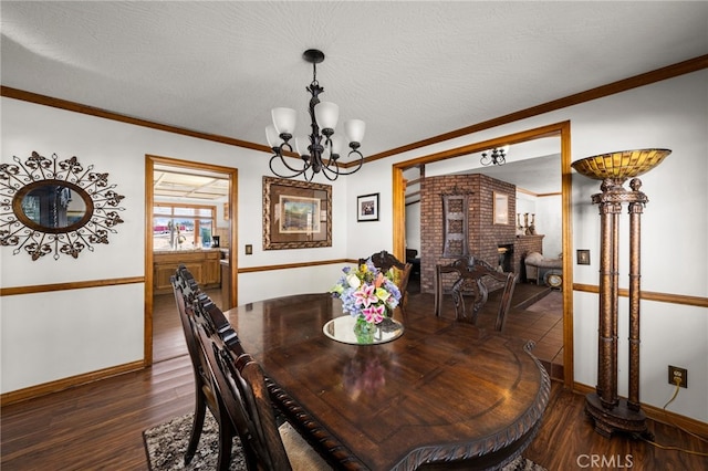 dining room with crown molding, a brick fireplace, dark hardwood / wood-style floors, and a chandelier