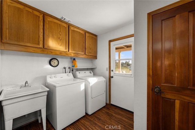 washroom featuring dark hardwood / wood-style flooring, sink, washing machine and dryer, and cabinets