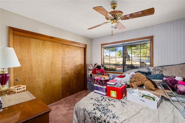 carpeted bedroom featuring ceiling fan, a closet, and a textured ceiling