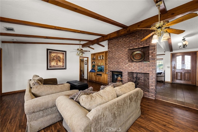 living room with a brick fireplace, dark hardwood / wood-style floors, beamed ceiling, and ceiling fan