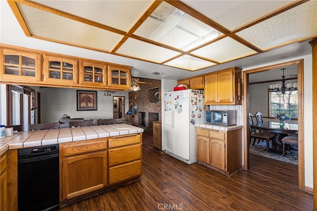 kitchen featuring an inviting chandelier, dark wood-type flooring, tile countertops, and white fridge with ice dispenser