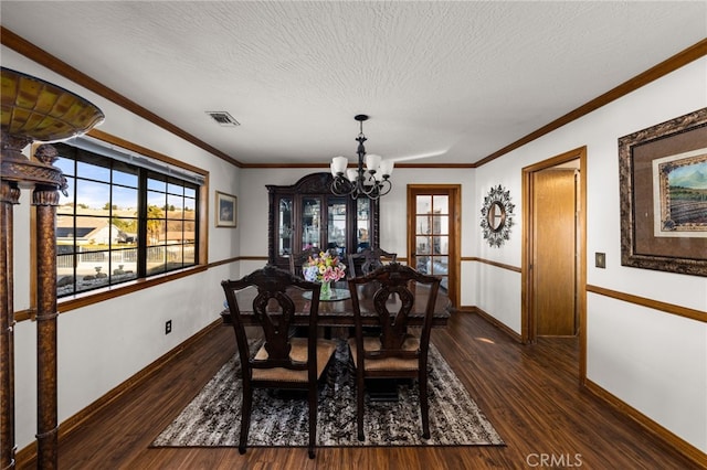 dining space featuring an inviting chandelier, ornamental molding, dark hardwood / wood-style floors, and a textured ceiling