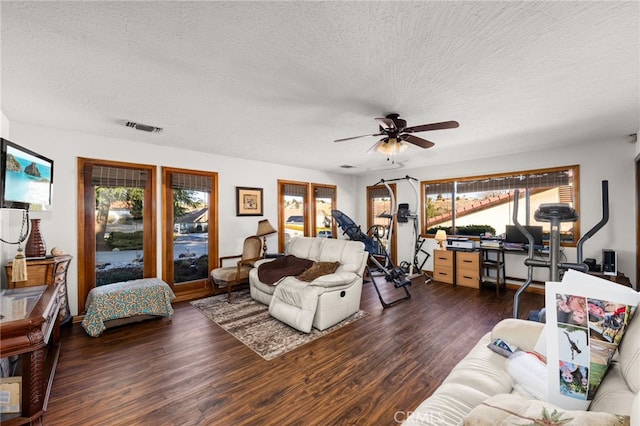 living room featuring dark hardwood / wood-style flooring, ceiling fan, and a textured ceiling