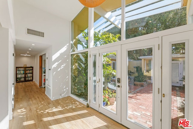 entryway featuring a towering ceiling, french doors, and light wood-type flooring