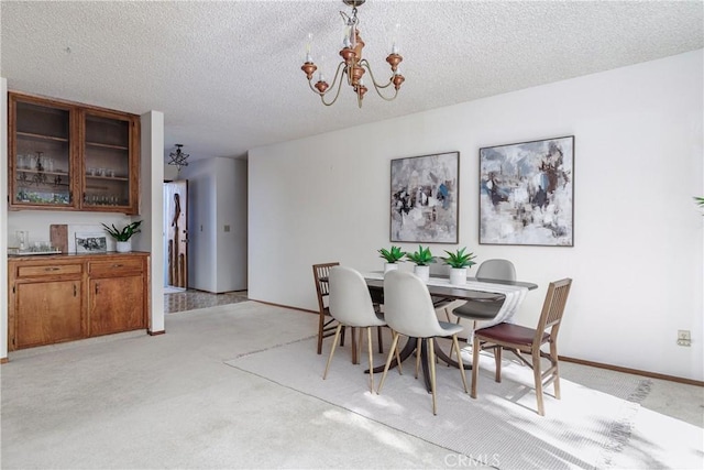 carpeted dining room featuring a notable chandelier and a textured ceiling