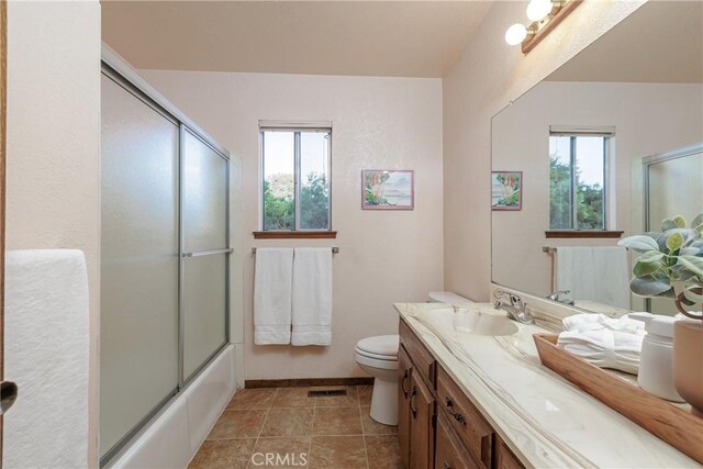 full bathroom featuring toilet, vanity, combined bath / shower with glass door, and tile patterned flooring