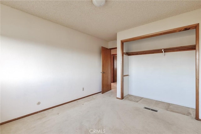 unfurnished bedroom featuring a closet, light carpet, and a textured ceiling