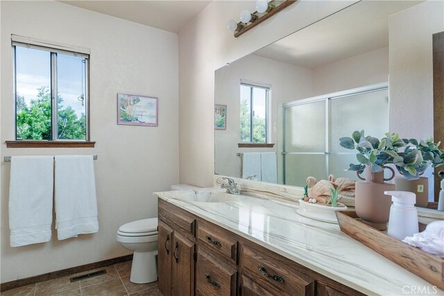 bathroom with tile patterned flooring, vanity, toilet, and walk in shower