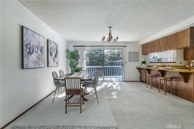 carpeted dining space with an inviting chandelier and a textured ceiling