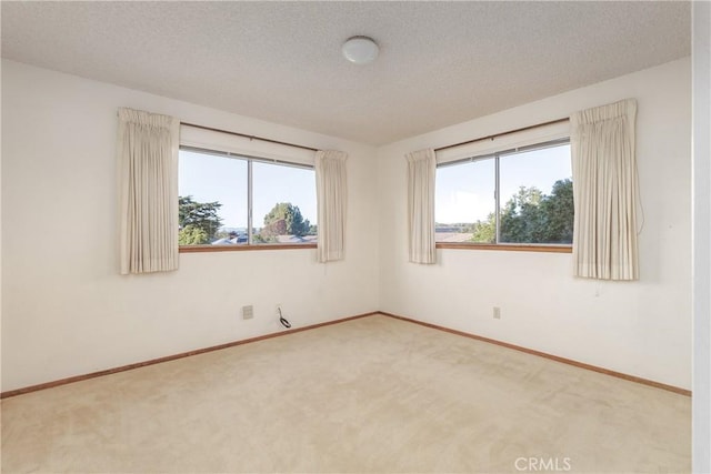 unfurnished room featuring a textured ceiling, a healthy amount of sunlight, and carpet