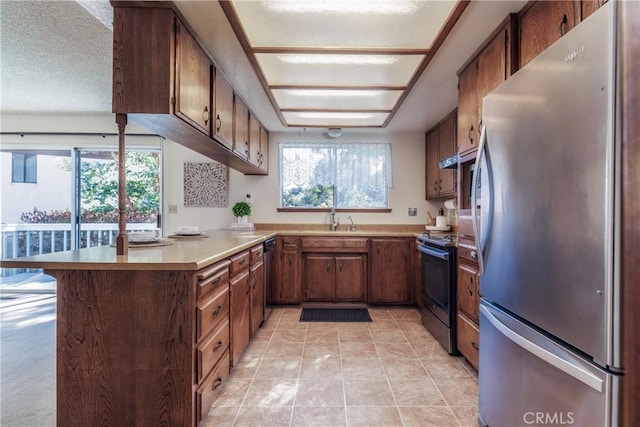 kitchen with stainless steel appliances, kitchen peninsula, sink, and a wealth of natural light