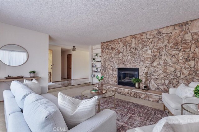 living room featuring a stone fireplace, a textured ceiling, and built in shelves