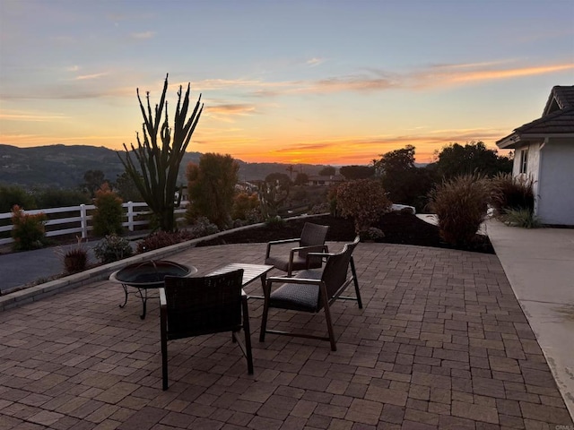 patio terrace at dusk featuring an outdoor fire pit and a mountain view