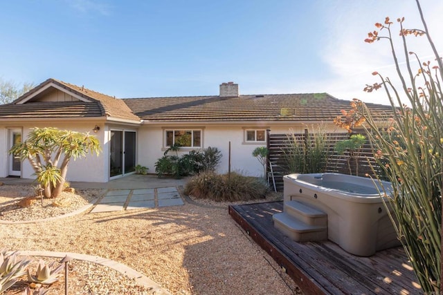 rear view of property featuring a hot tub and a patio