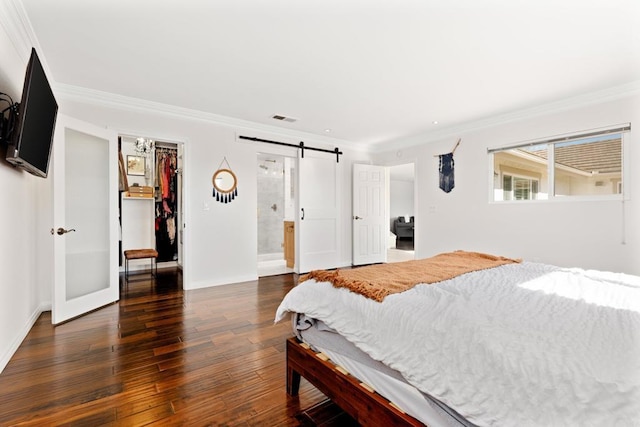 bedroom with dark hardwood / wood-style floors, a walk in closet, ornamental molding, and a barn door