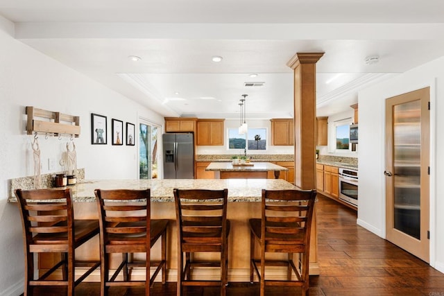 kitchen featuring dark wood-type flooring, stainless steel appliances, light stone counters, a kitchen bar, and kitchen peninsula