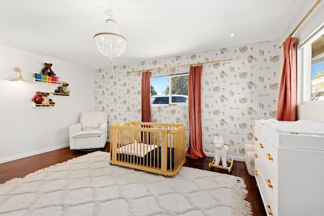 bedroom featuring hardwood / wood-style flooring, a crib, and an inviting chandelier