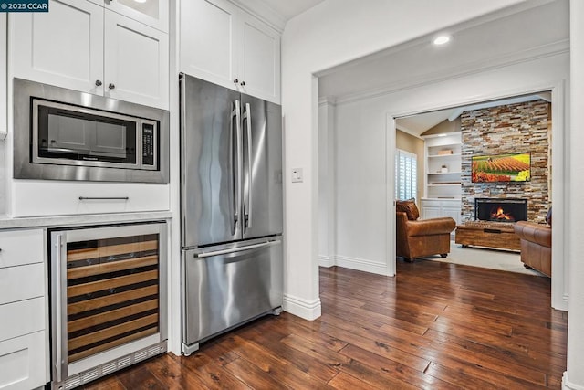 kitchen featuring white cabinetry, stainless steel appliances, wine cooler, a fireplace, and dark hardwood / wood-style flooring