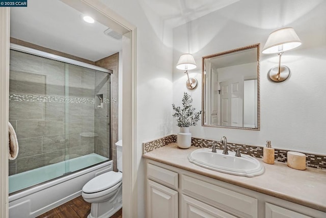 full bathroom with vanity, combined bath / shower with glass door, wood-type flooring, and toilet