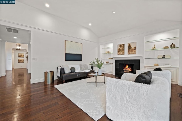 living room featuring a tiled fireplace, vaulted ceiling, dark hardwood / wood-style floors, and built in features