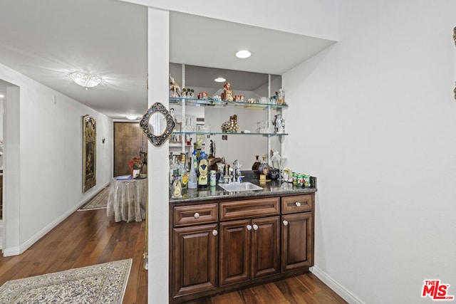 bar with dark stone counters, dark hardwood / wood-style flooring, and sink