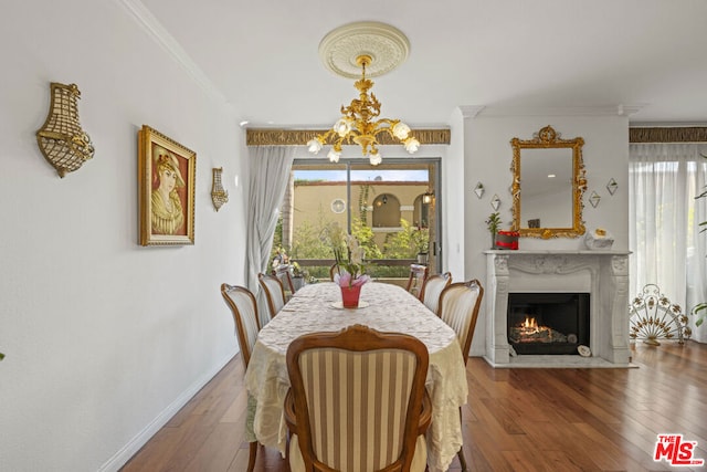 dining space with ornamental molding, a chandelier, a high end fireplace, and wood-type flooring