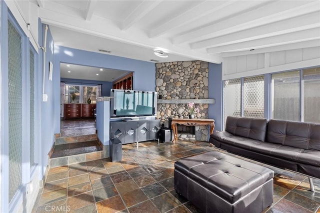 living room featuring beamed ceiling and a fireplace