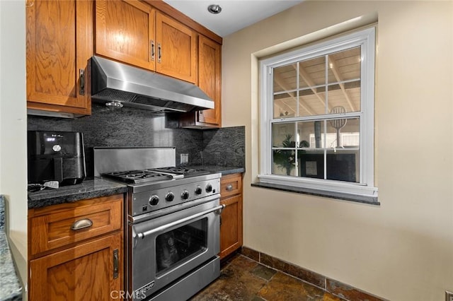 kitchen featuring dark stone countertops, high end range, and backsplash