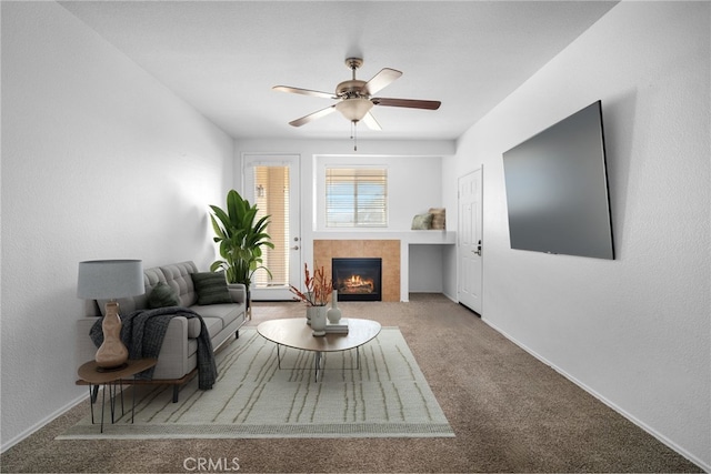 carpeted living room featuring a tiled fireplace and ceiling fan