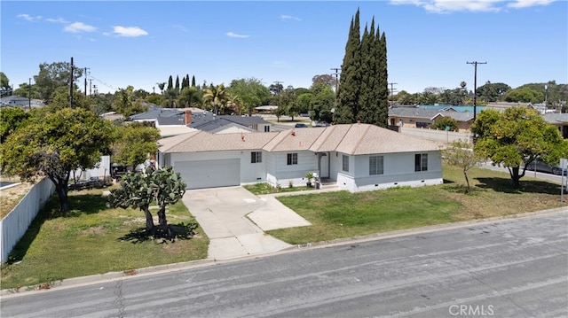 ranch-style home with an attached garage, a front lawn, fence, and concrete driveway