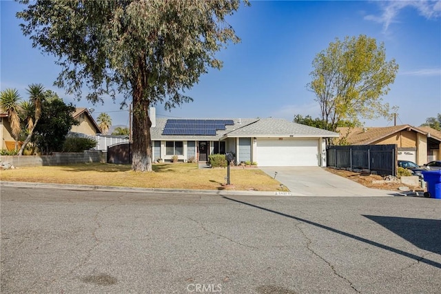 ranch-style house featuring a garage, a front lawn, and solar panels