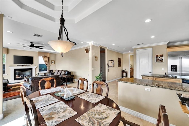 tiled dining area with ornamental molding, ceiling fan, and a tray ceiling