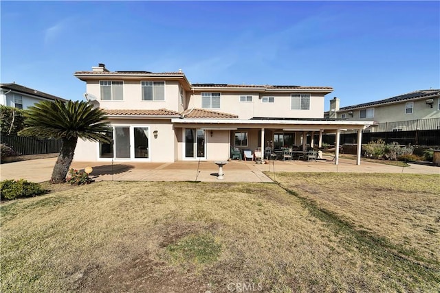 back of property with a yard, a patio area, and solar panels