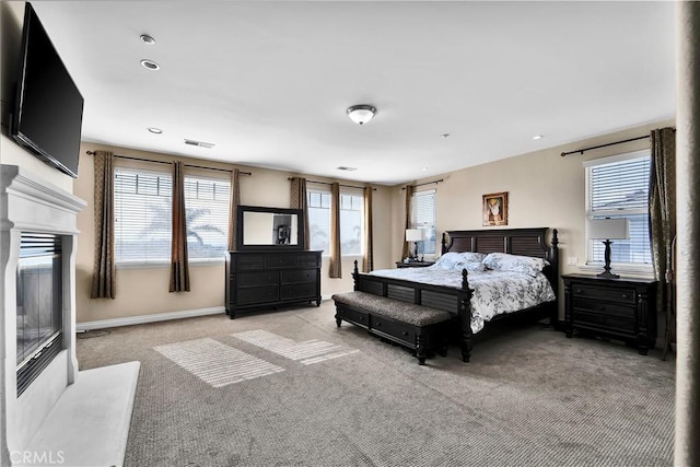 carpeted bedroom featuring a premium fireplace and multiple windows