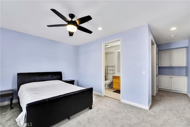 bedroom featuring ensuite bath, light colored carpet, and ceiling fan